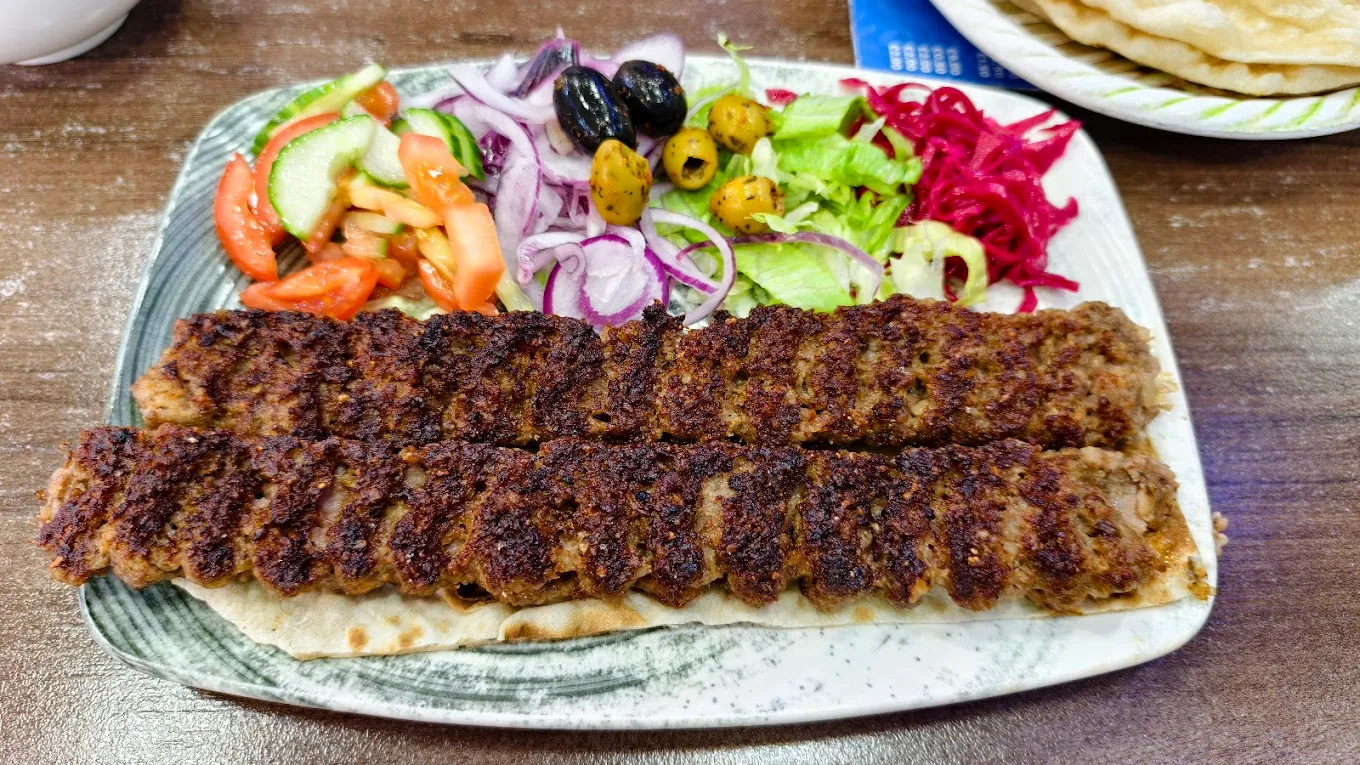 two skewers of grilled minced meat kebab served over flatbread from Pshdar Kurdish Restaurant in Liverpool