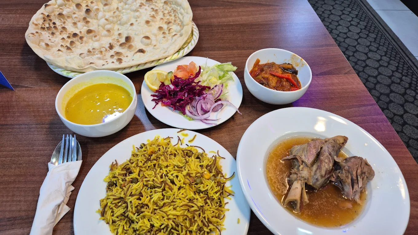 Kurdish meal from Pshdar Kurdish Restaurant in Liverpool, featuring lamb shank and broth, saffron rice, Nan flatbread, lentil soup, and a side salad.